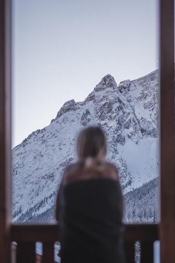 Eine Frau blickt auf die verschneiten Dolomiten