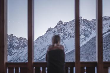 Eine Frau blickt auf die verschneiten Dolomiten