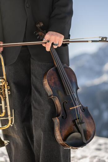 Eine Frau hält in einer Hand eine Trompete und in der anderen Hand eine Violine
