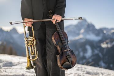 Eine Frau hält in einer Hand eine Trompete und in der anderen Hand eine Violine