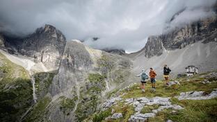 Zwei Frauen und ein Mann blicken auf die Dolomiten
