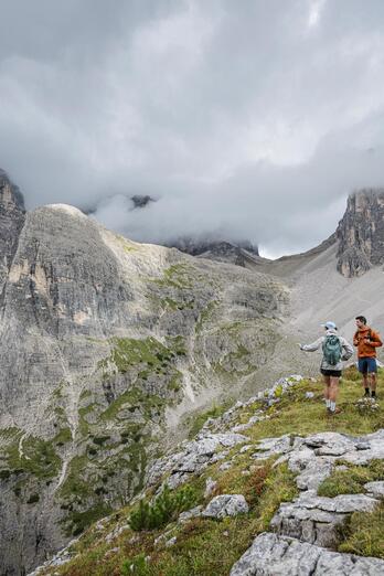 Zwei Frauen und ein Mann blicken auf die Dolomiten