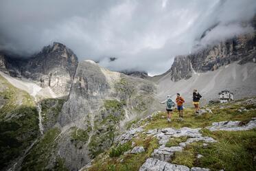 Zwei Frauen und ein Mann blicken auf die Dolomiten