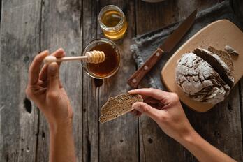 Eine Frau streicht Honig auf ein Brot