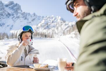 Ein Mann und eine Frau in Skiausrüstung trinken Kaffee