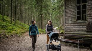 Ein Mann und eine Frau spazieren mit dem Kinderwagen durch den Wald