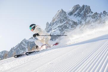 Ein Skifahrer fährt auf einer verschneiten Piste bergab