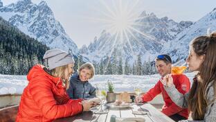 Drei Frauen und ein Mann sitzen an einem Tisch und trinken einen Aperitif