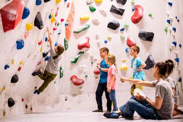 Eine Gruppe von Kindern klettert in einer Boulderhalle